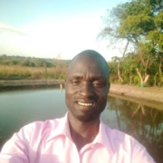 Daniel Oloya taking a seflie with a fish pond in the background