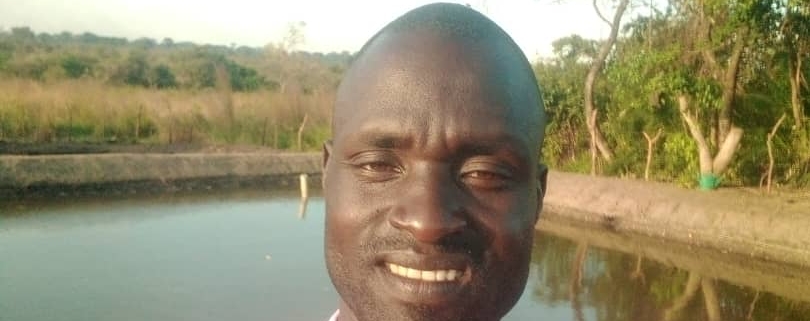 Daniel Oloya taking a seflie with a fish pond in the background